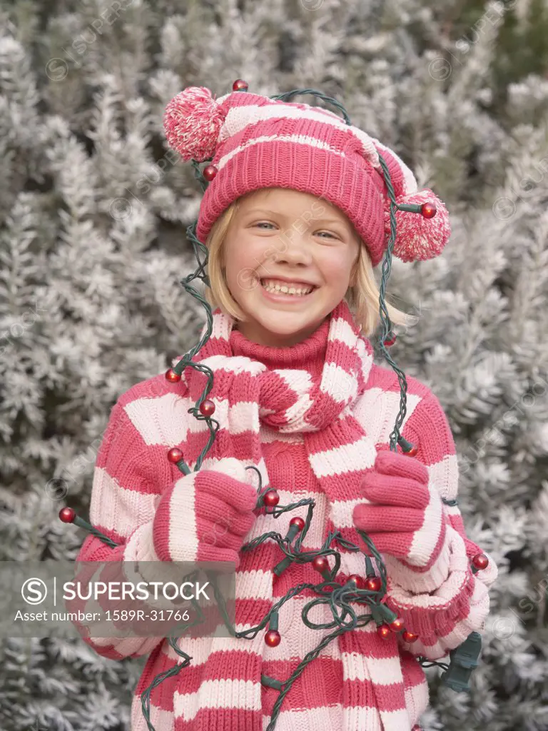 Young girl in winter clothing with Christmas lights