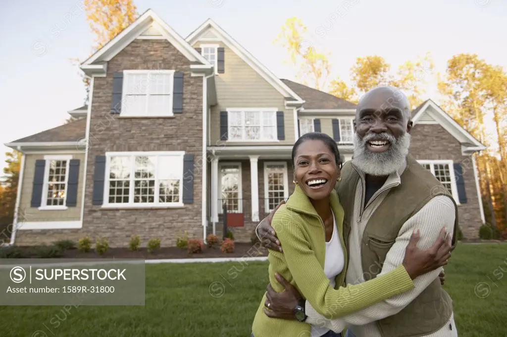 Portrait of senior African couple in front of house