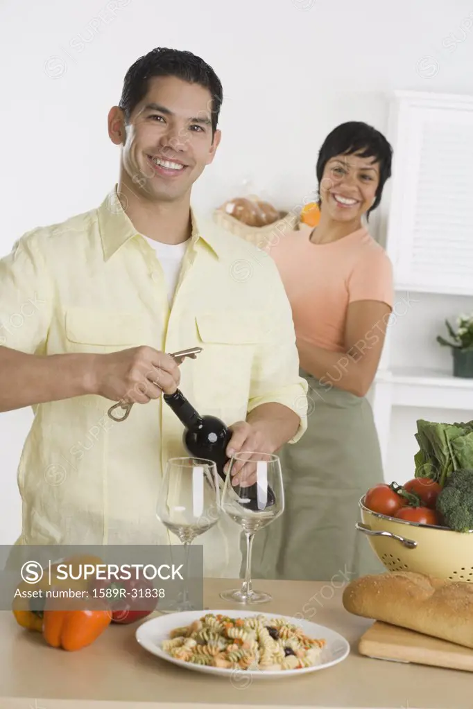 Hispanic man opening wine bottle