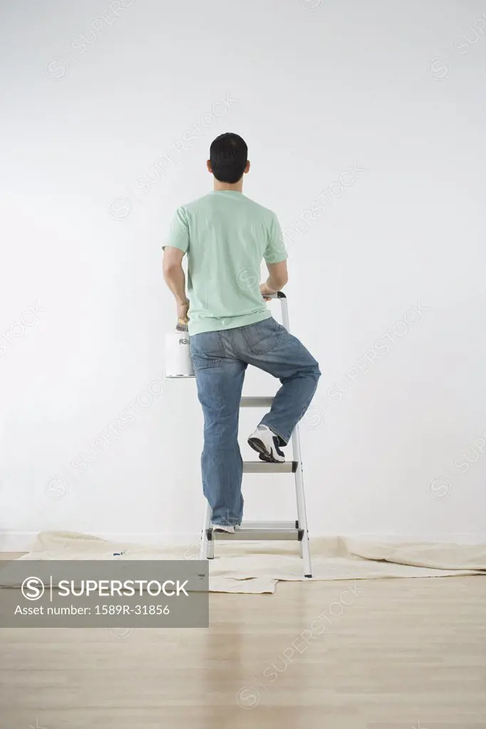 Hispanic man climbing ladder