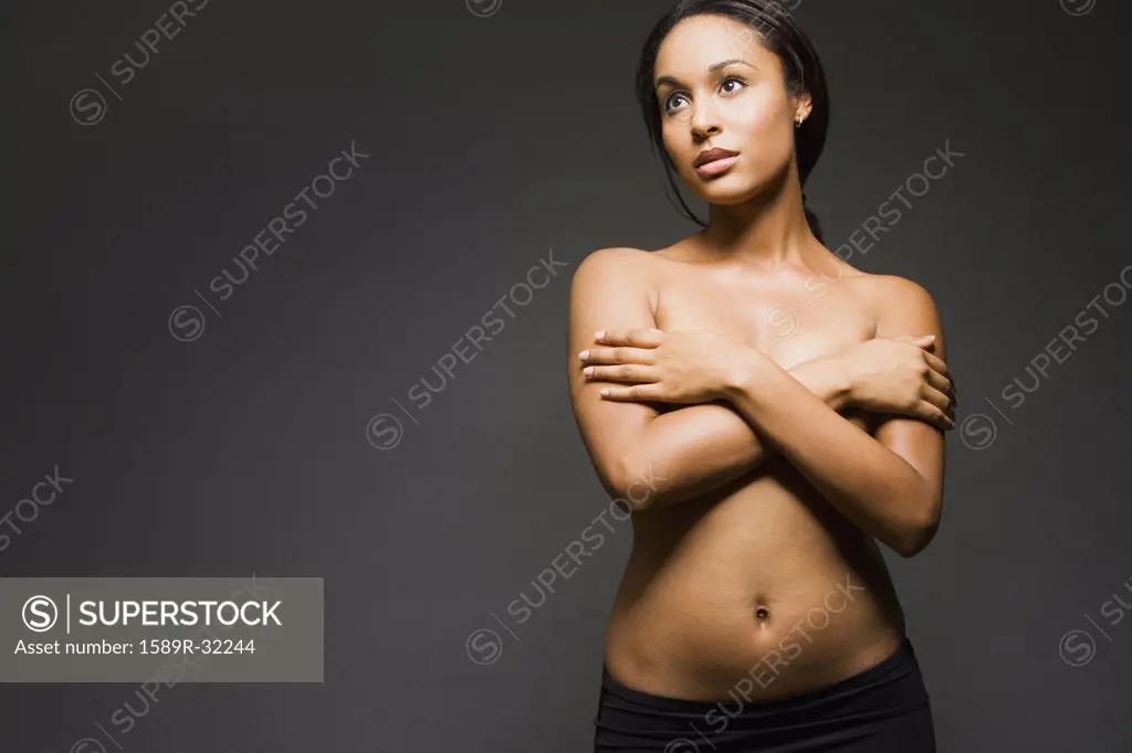 Semi-nude Hispanic woman with arms covering breasts