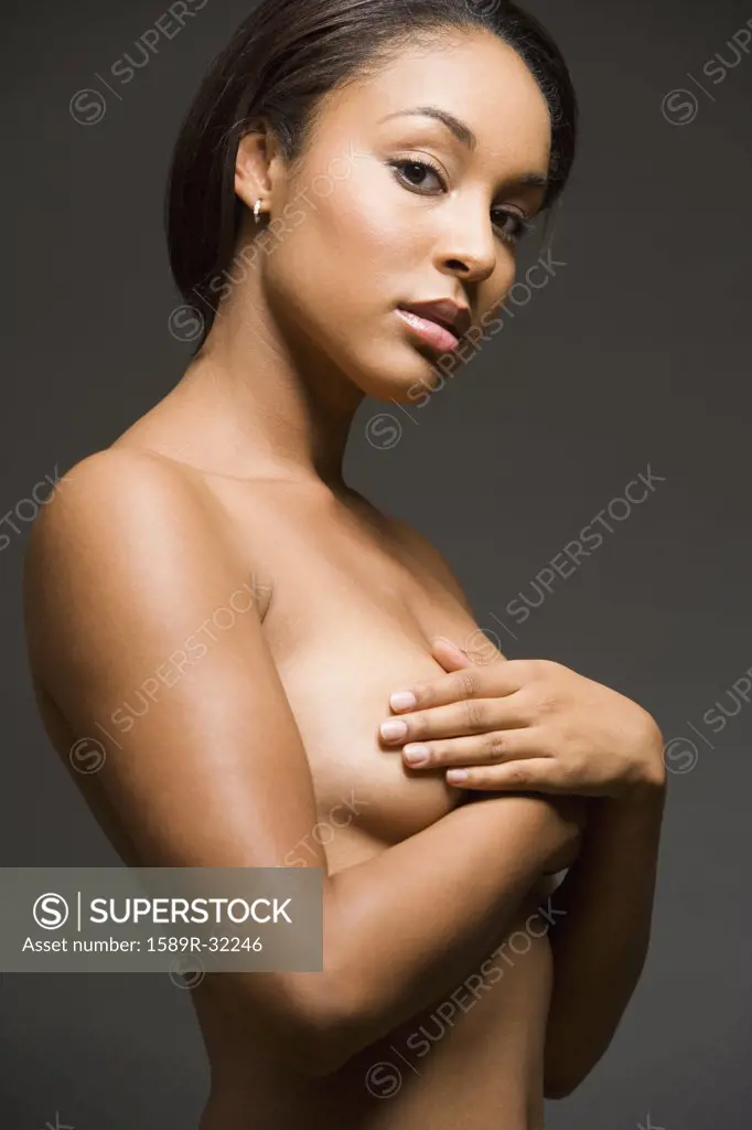 Nude Hispanic woman with arms covering breasts
