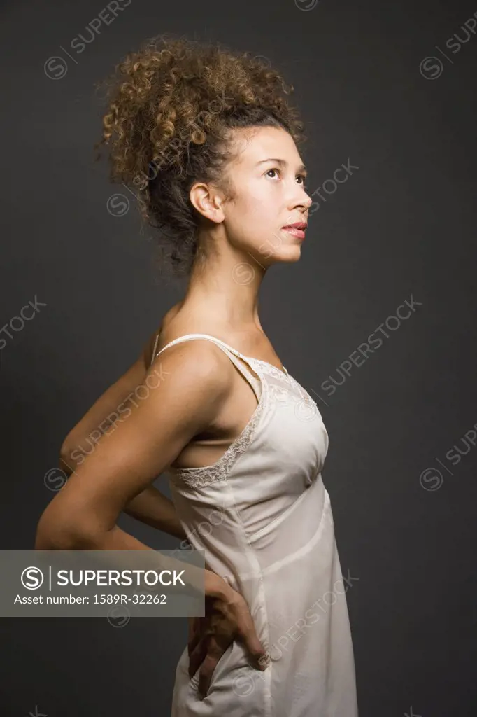 Studio shot of Hispanic woman wearing slip with hands on back