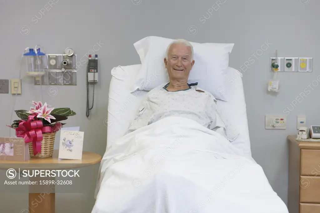 Senior male patient smiling in hospital bed
