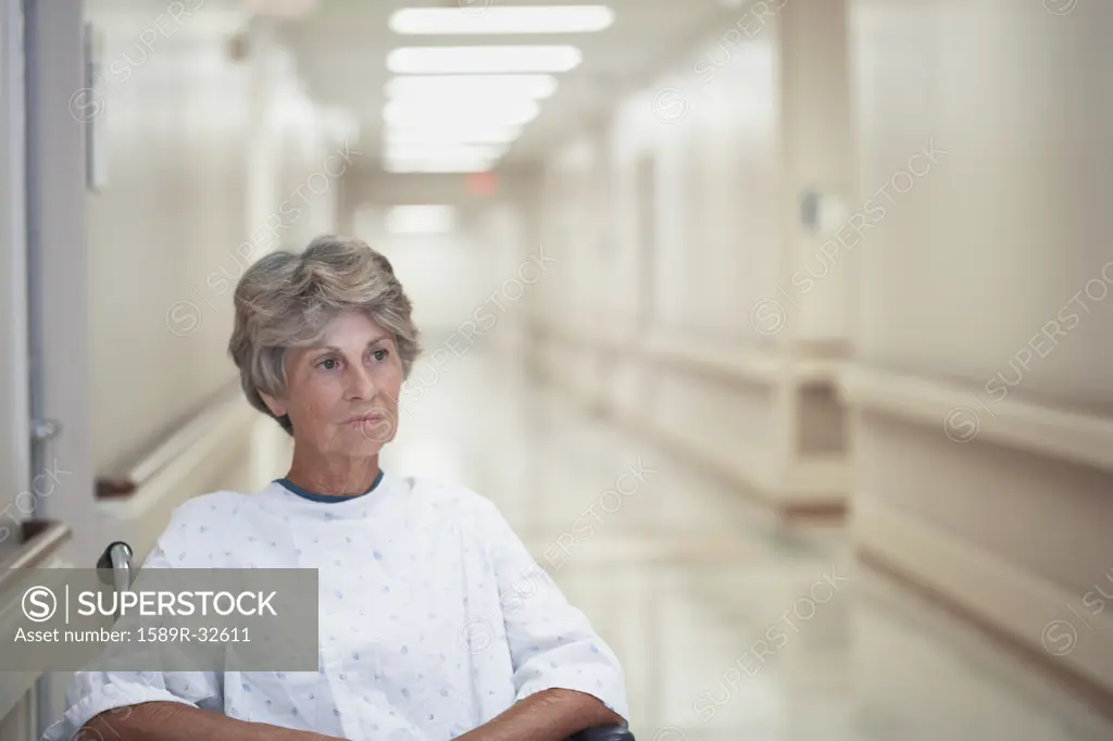 Senior female patient sitting in wheelchair at hospital corridor