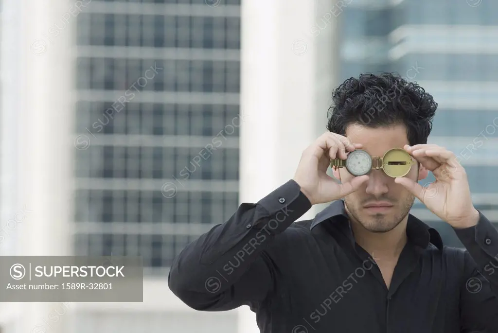 Hispanic man holding watch over eyes