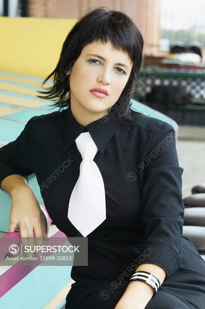 Young Hispanic woman wearing necktie sitting at counter of carnival booth