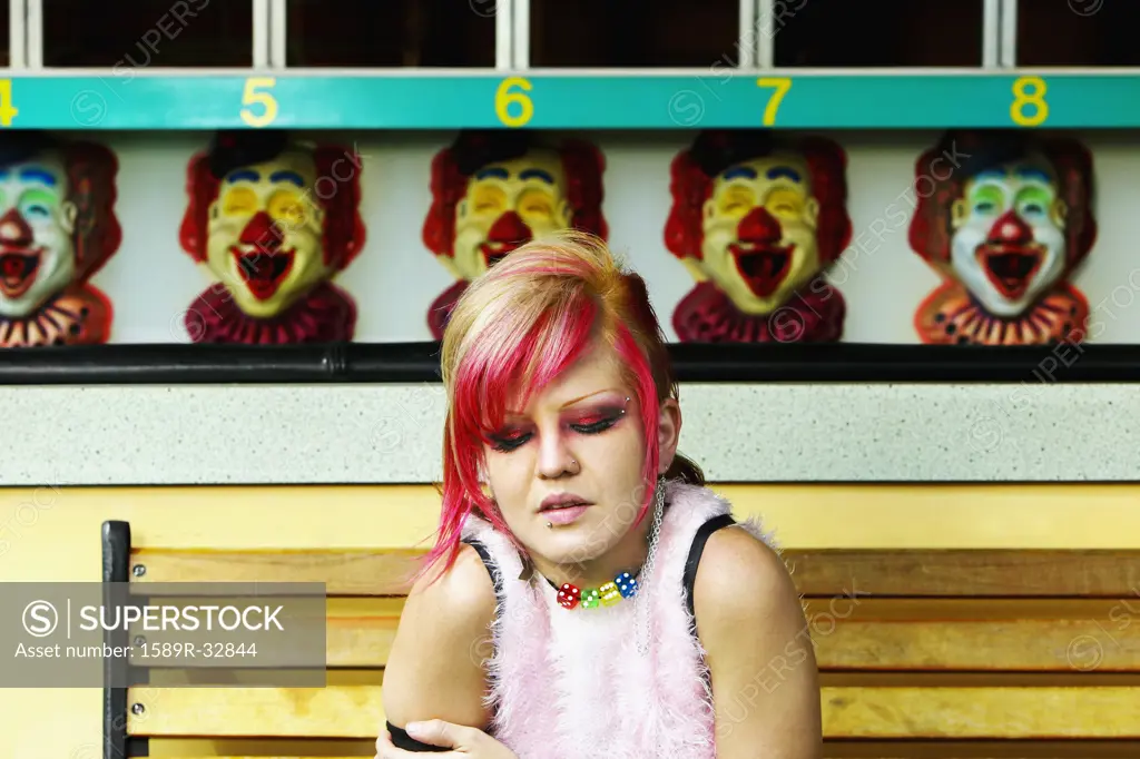 Young Hispanic punk female sitting in front of carnival booth