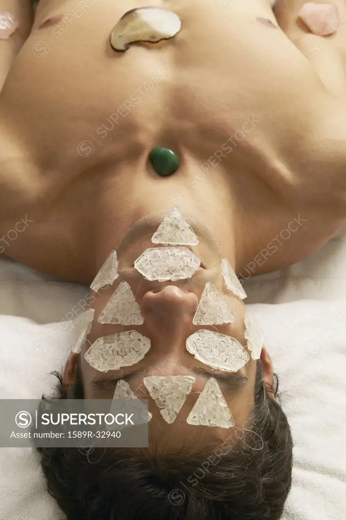 Hispanic man receiving stone and crystal spa treatment