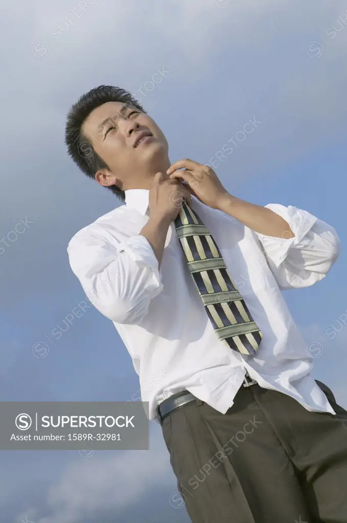 Asian businessman adjusting necktie