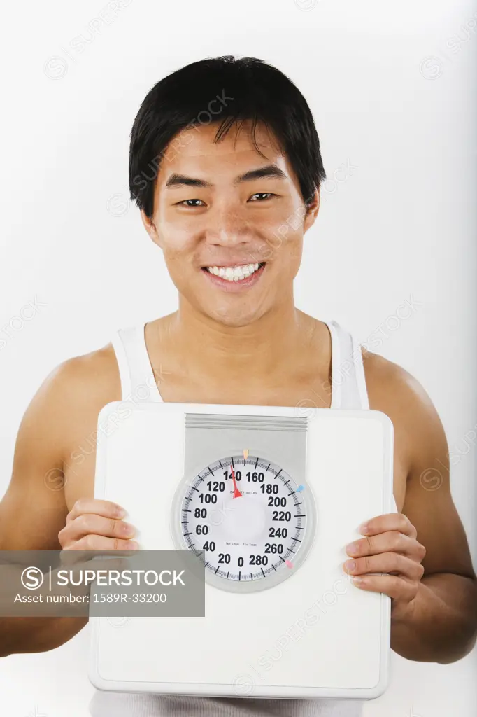 Portrait of Asian man holding bathroom scale
