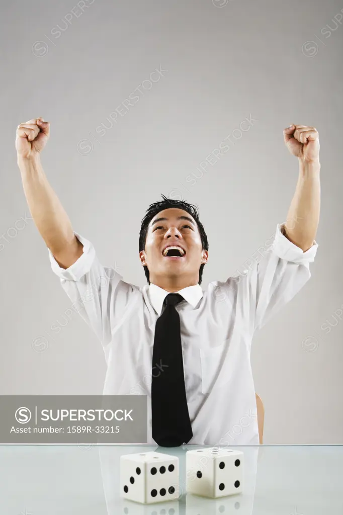 Asian man cheering next to dice
