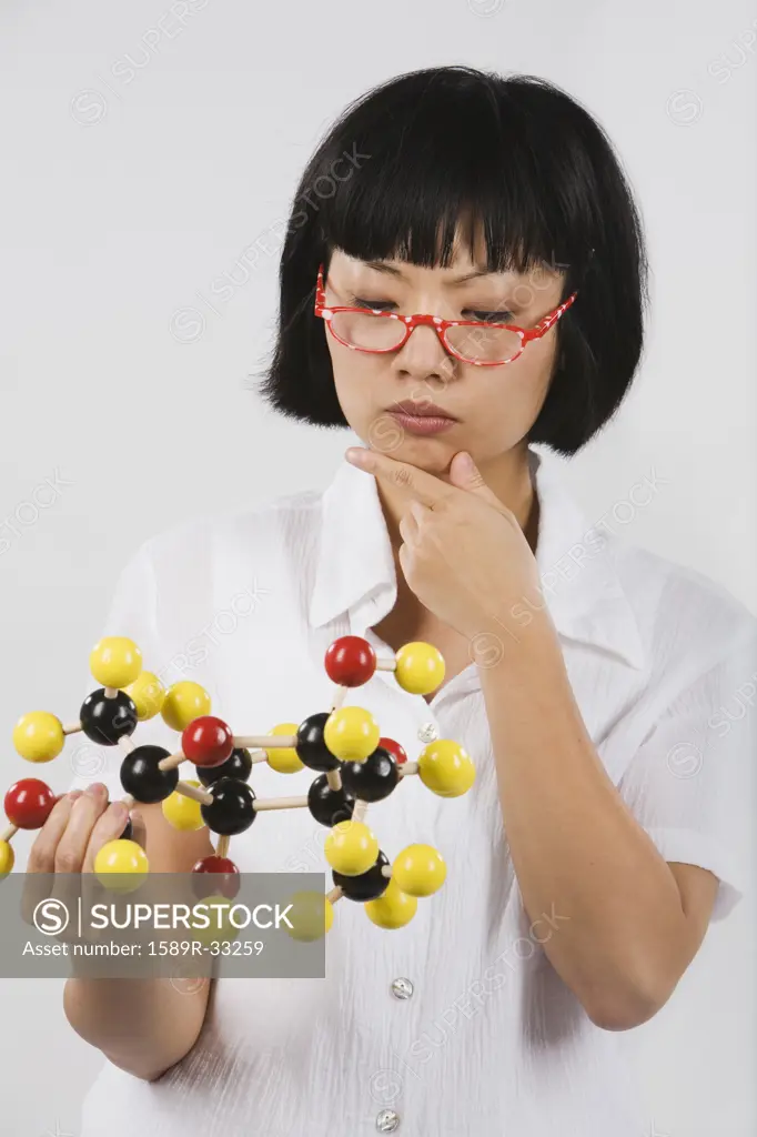Asian female scientist looking at chemical model