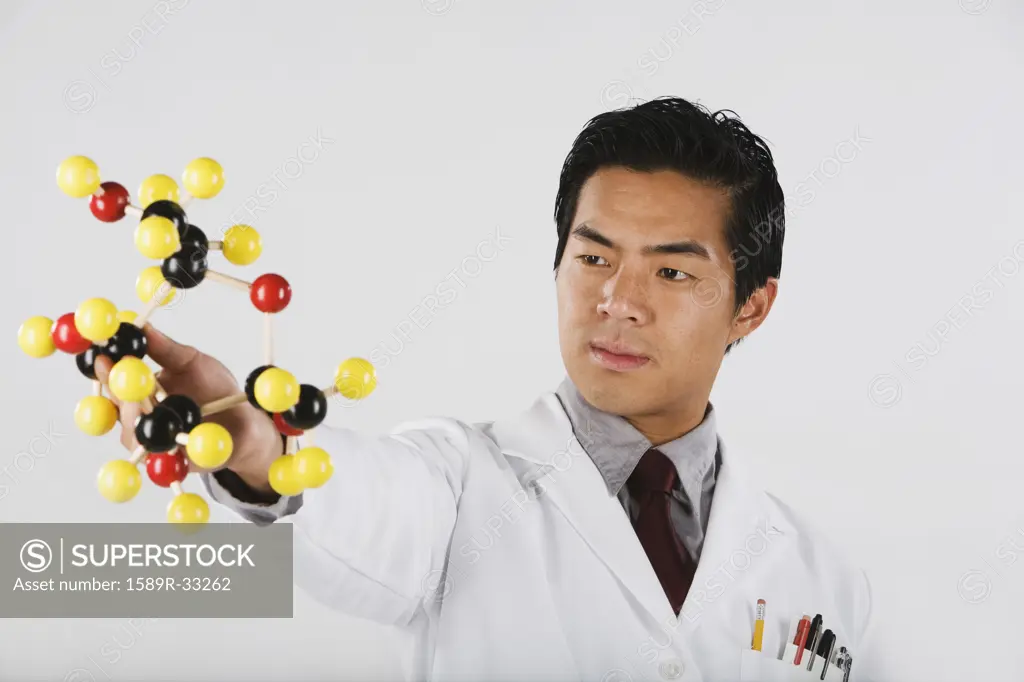 Asian male scientist looking at chemical model