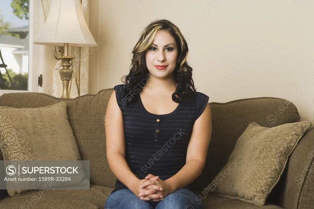 Portrait of Hispanic woman sitting on sofa