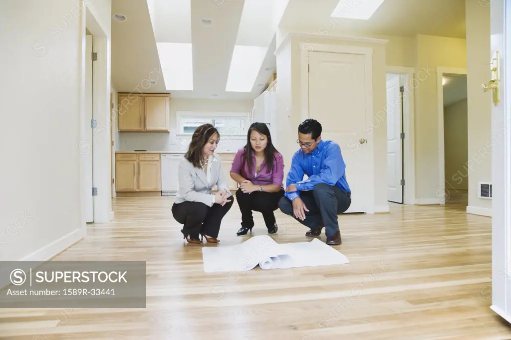 Asian couple looking at blueprints in new house