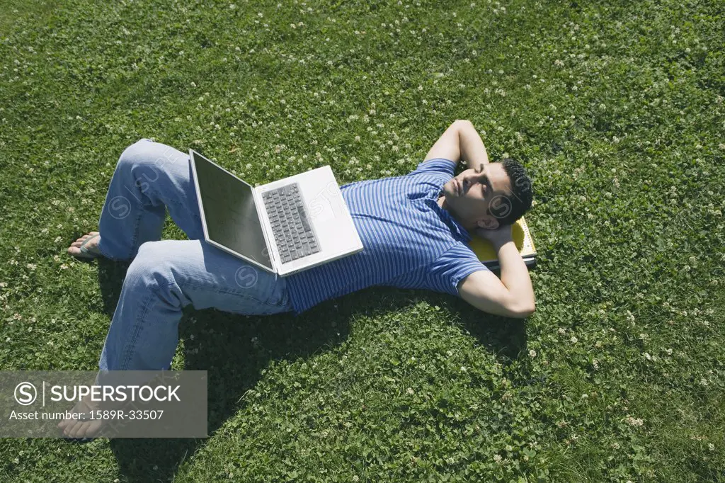 Asian male college student laying on grass