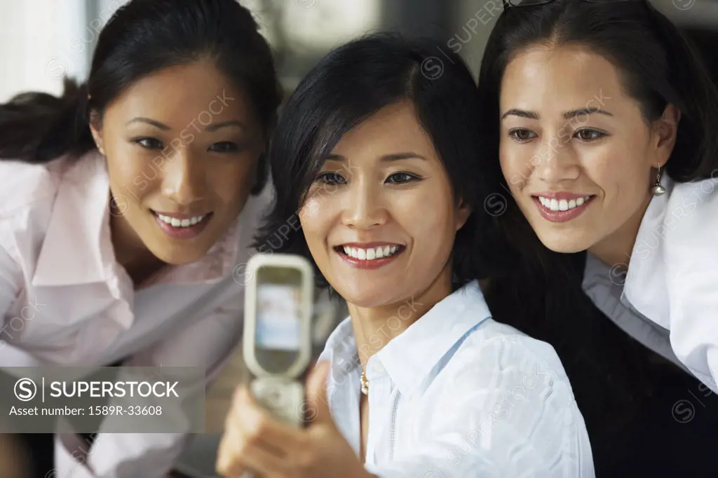 Asian businesswomen taking own photograph with cell phone