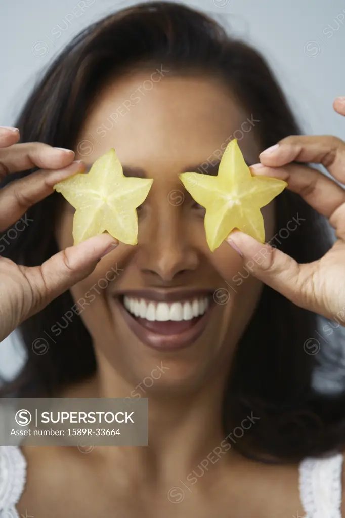 Asian woman holding star fruits over eyes