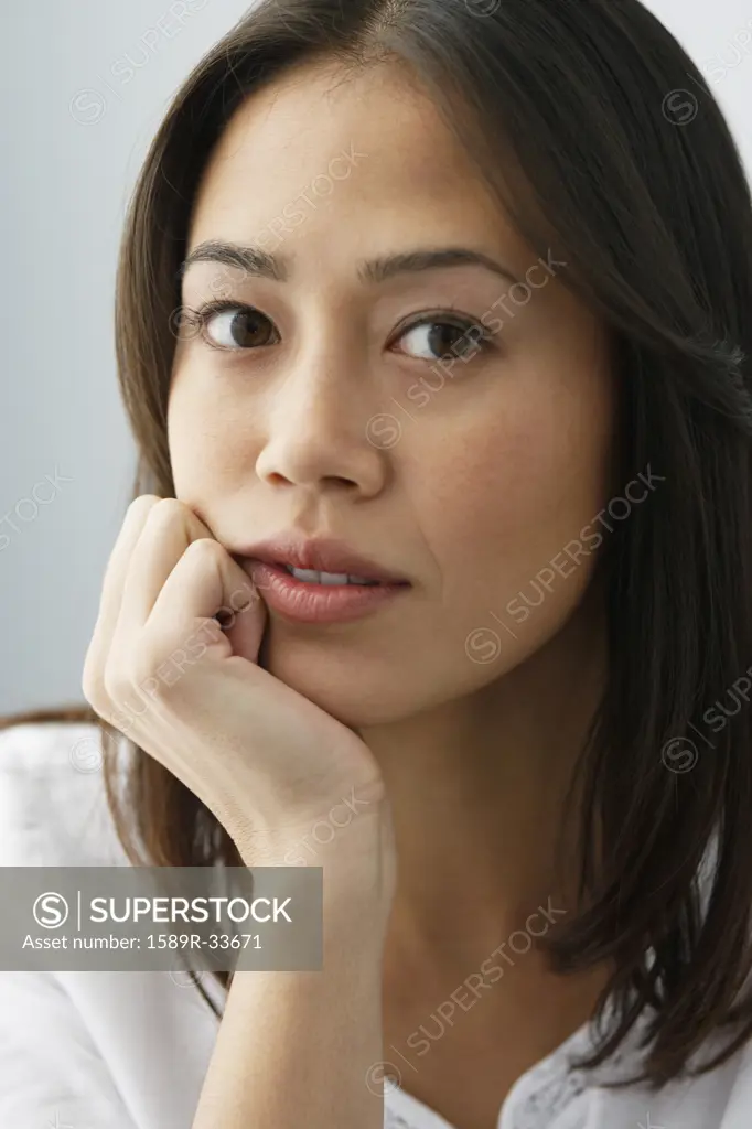 Asian woman resting chin in hand