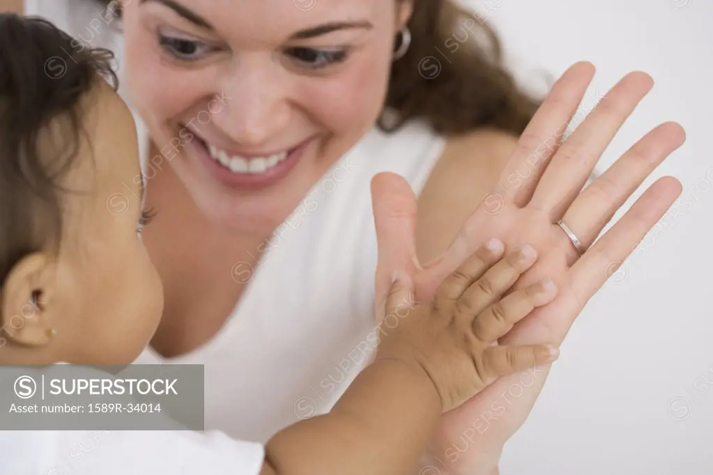 Hispanic mother and baby clapping hands