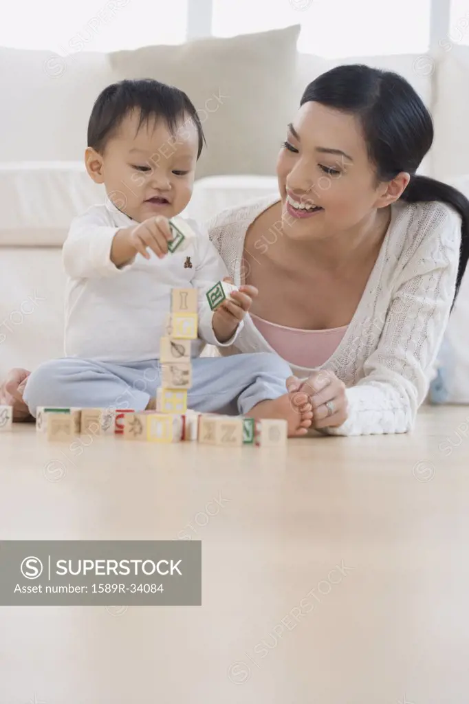 Asian mother and baby playing with blocks on floor