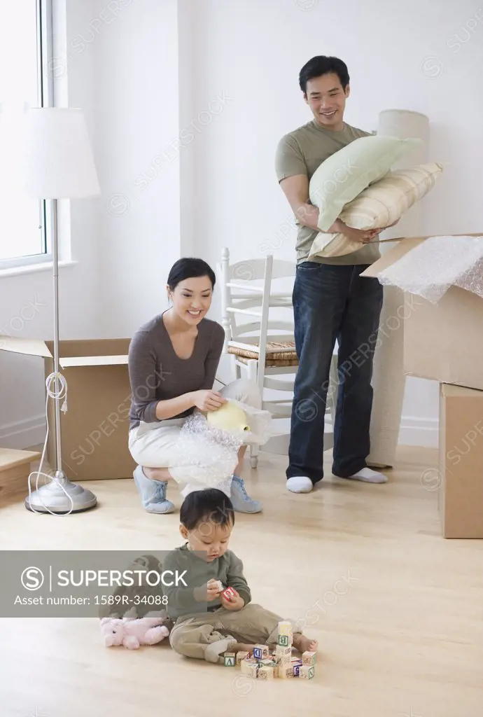Asian parents watching baby play with blocks on floor