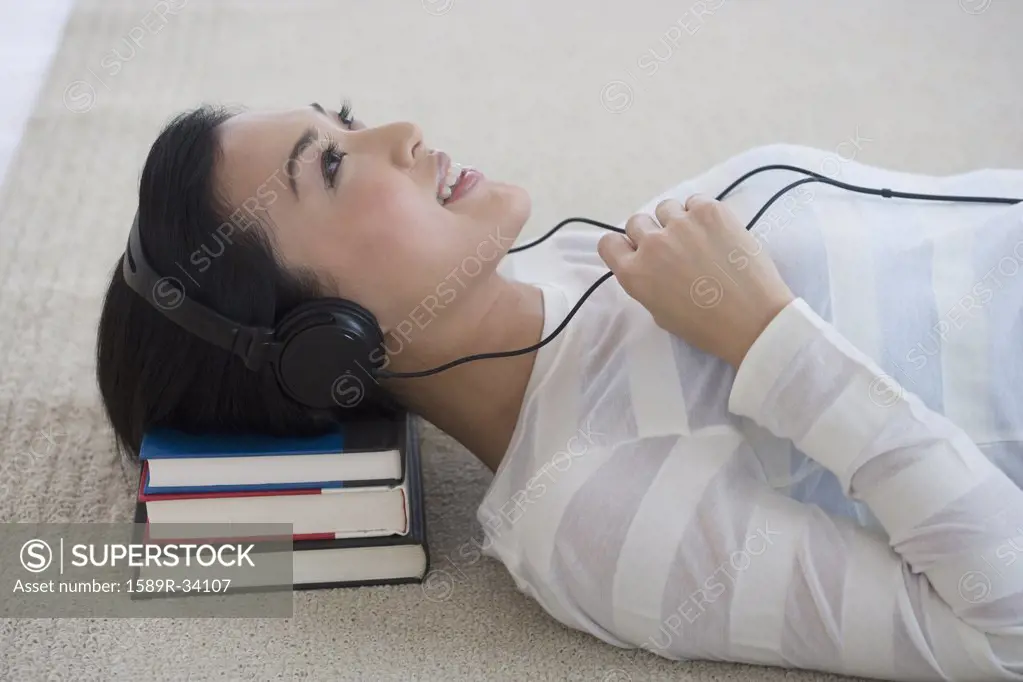 Asian woman listening to headphones on floor