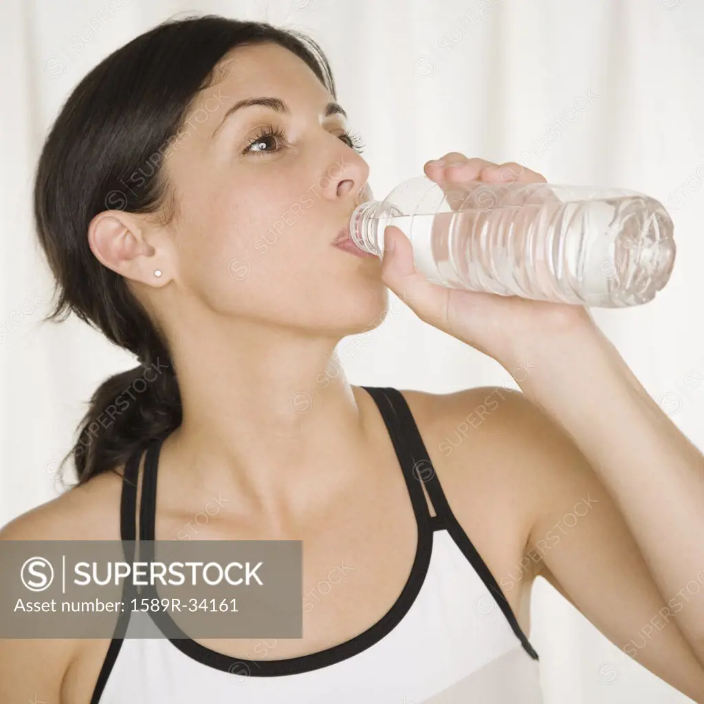 Hispanic woman drinking bottled water