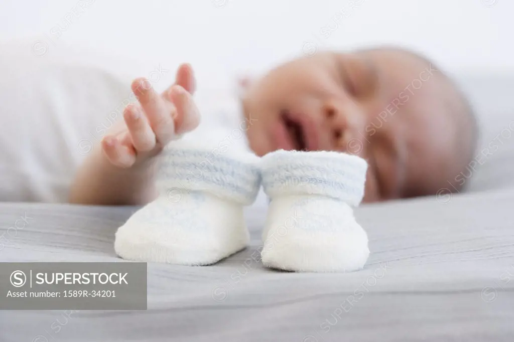 Close up of baby booties next to sleeping newborn baby