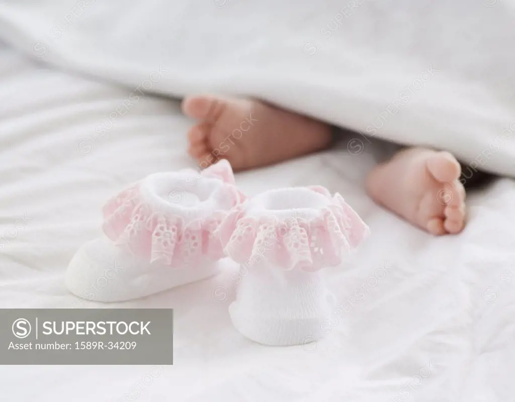 Baby booties next to newborn babys feet
