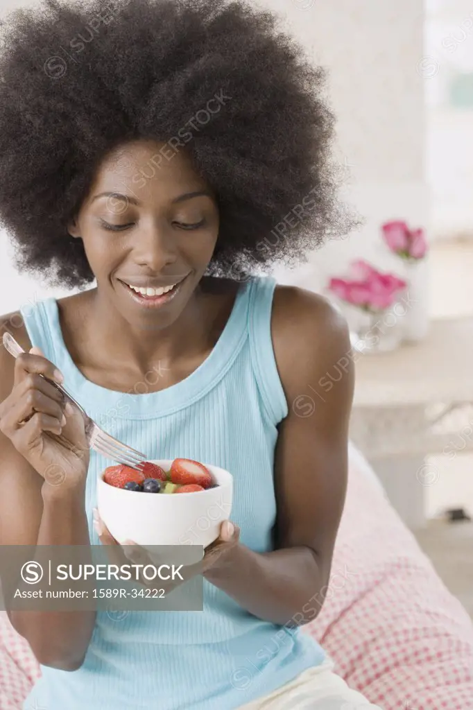 African woman eating bowl of fruit