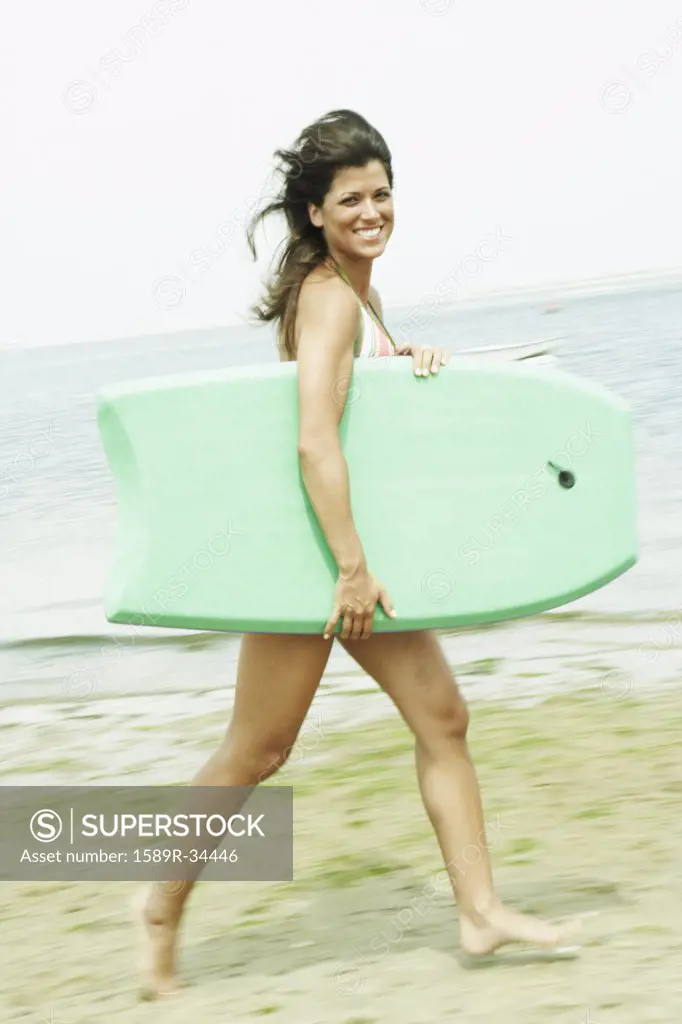 Woman carrying boogie board at beach