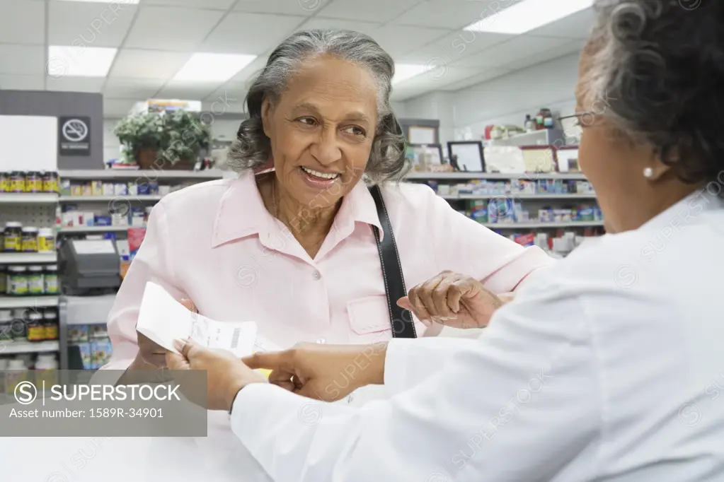 African female pharmacist discussing medication with senior customer