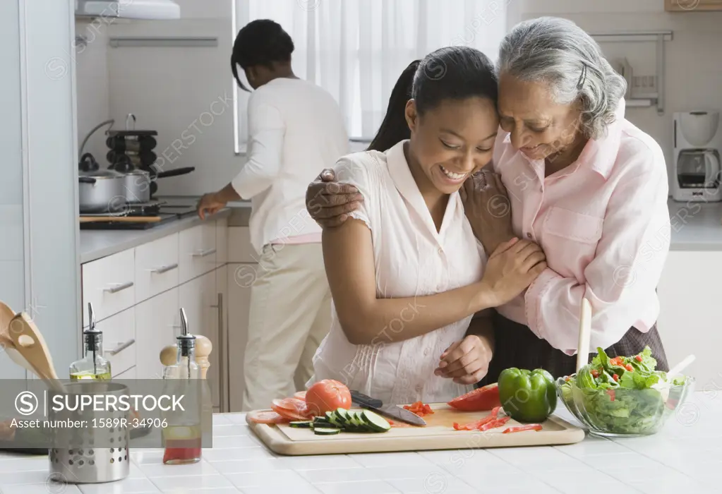 African grandmother and granddaughter preparing food in kitchen