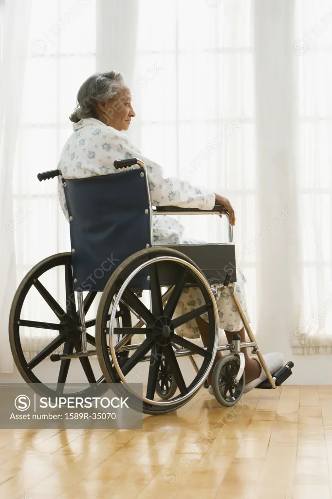 Senior African woman in wheelchair looking out window
