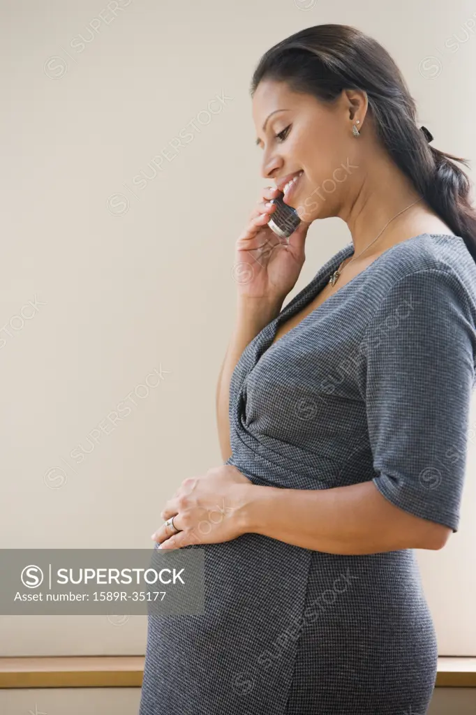 Pregnant Hispanic woman talking on cell phone