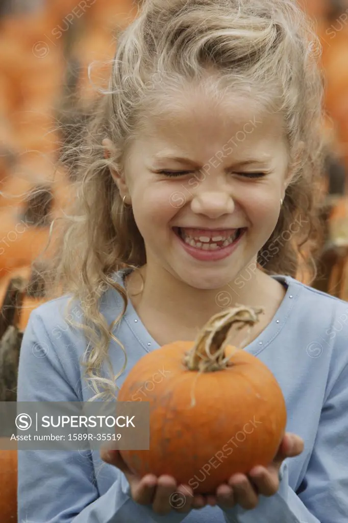Girl laughing and holding pumpkin
