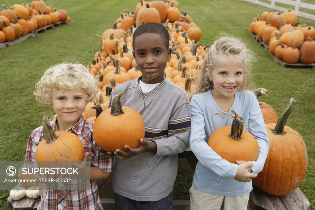 Portrait of children holding pumpkins
