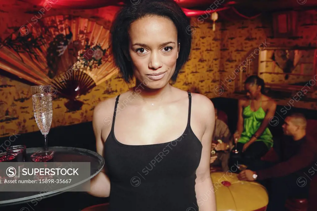 African cocktail waitress holding tray of drinks