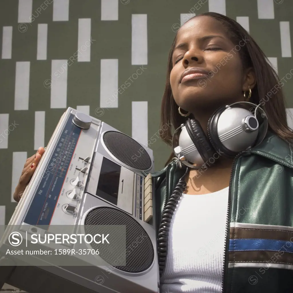 Low angle view of African woman listening to music on portable stereo