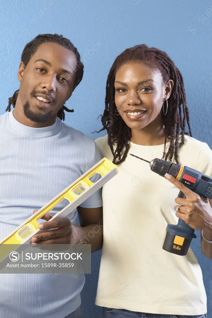 African couple with level and power drill 