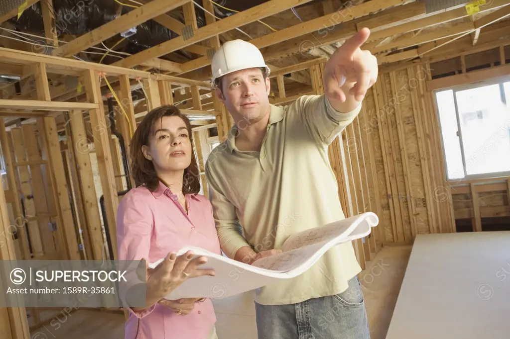 Couple with blueprints on construction site
