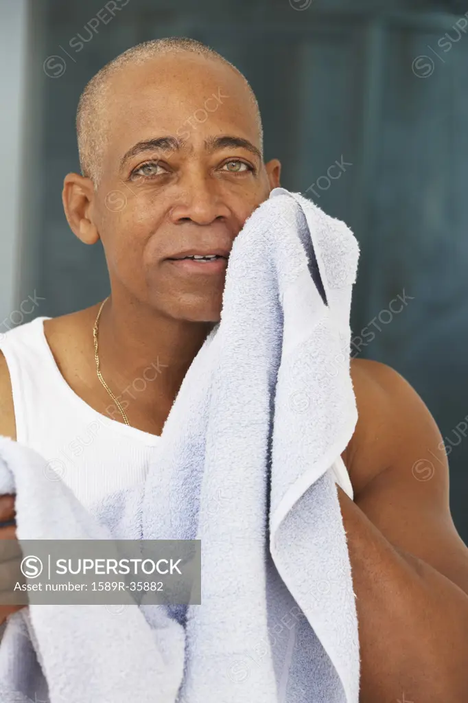 Senior African man drying face with towel