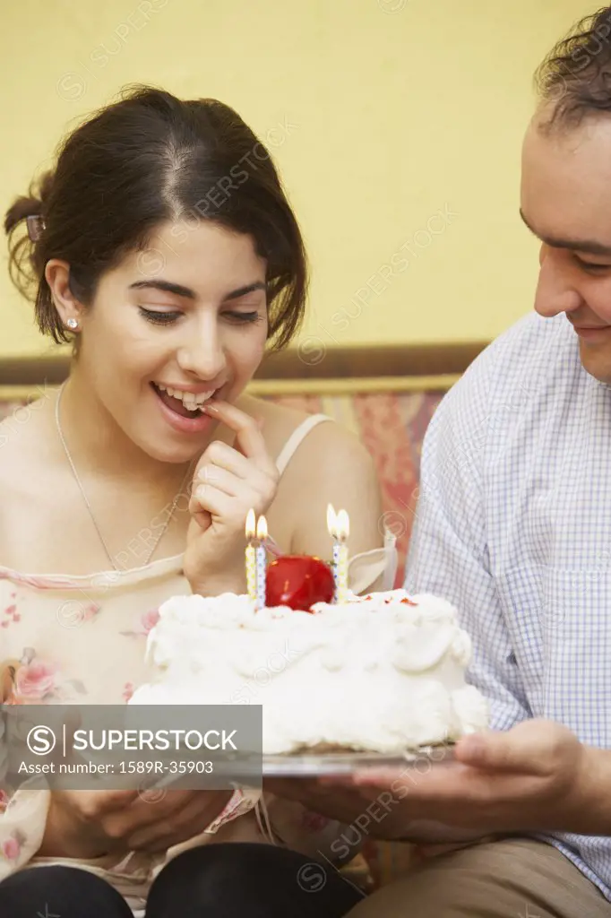 Hispanic man giving girlfriend birthday cake