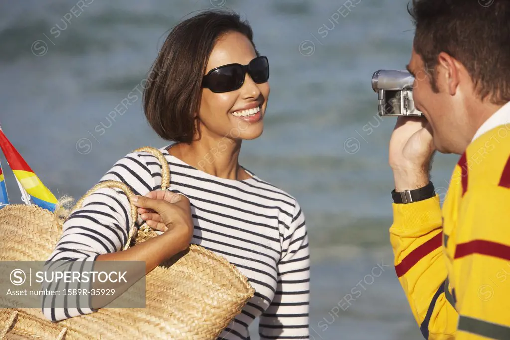 Indian man video recording girlfriend at beach