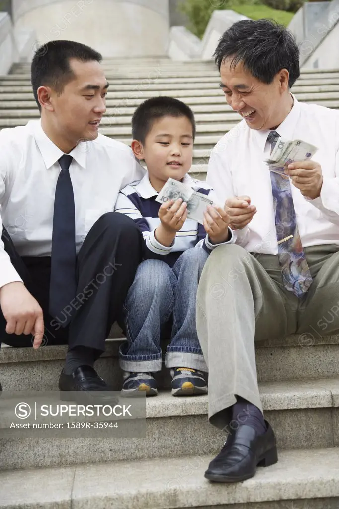 Asian grandfather, father and son looking at money
