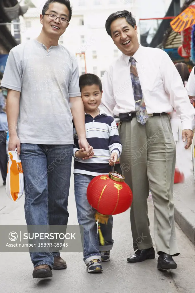 Asian grandfather, father and son walking on sidewalk