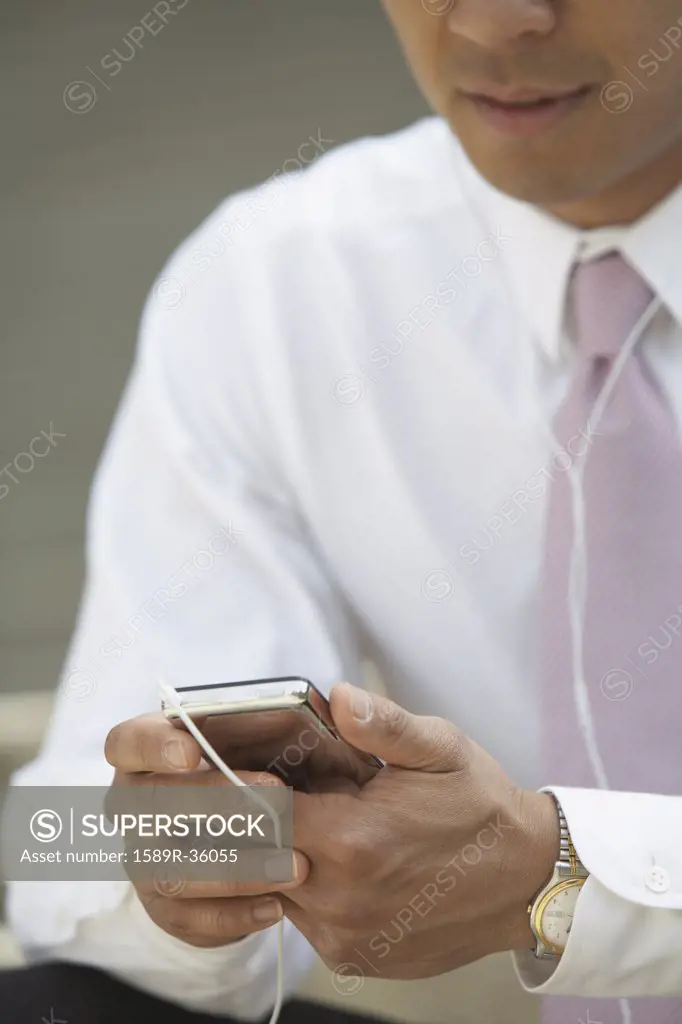 Asian businessman listening to mp3 player