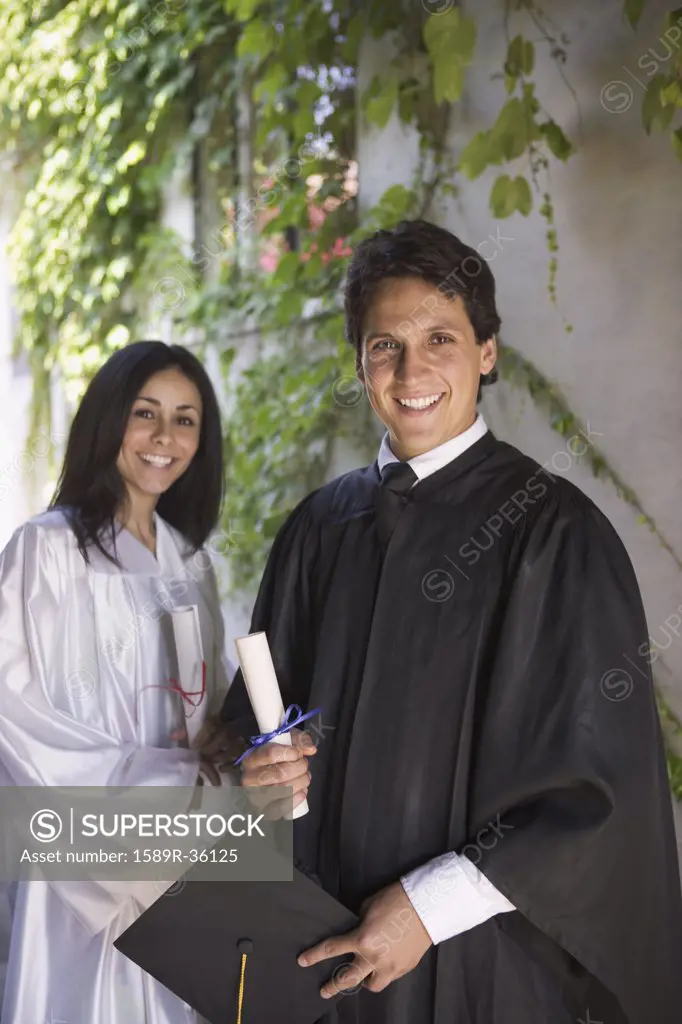 Graduating man and woman holding diplomas